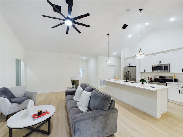 living room featuring ceiling fan, vaulted ceiling, sink, and light hardwood / wood-style flooring