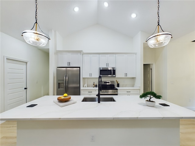 kitchen featuring white cabinets, appliances with stainless steel finishes, a kitchen island with sink, and pendant lighting