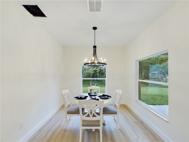 dining room with light hardwood / wood-style flooring, plenty of natural light, and an inviting chandelier