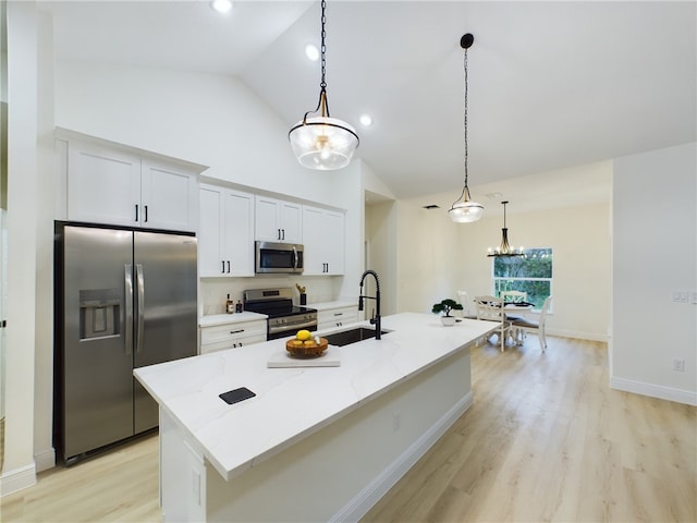 kitchen with sink, stainless steel appliances, light stone counters, a kitchen island with sink, and white cabinets