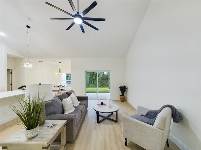 living room with ceiling fan, light hardwood / wood-style floors, and vaulted ceiling