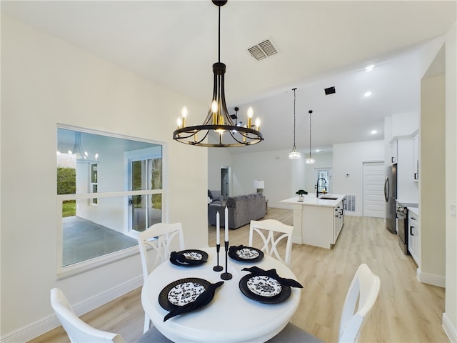 dining area featuring a chandelier, light hardwood / wood-style flooring, and sink