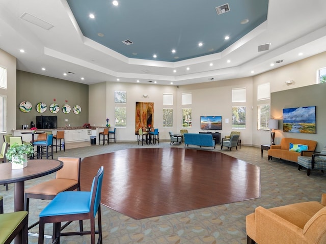 interior space with a high ceiling, a tray ceiling, and light hardwood / wood-style floors