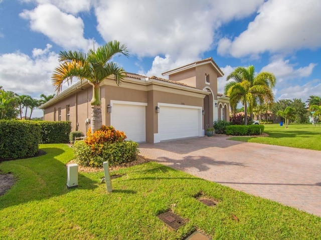 1745 Belmont Cir SW, Vero Beach, FL 32968 - mediterranean / spanish-style home featuring decorative driveway, stucco siding, an attached garage, a front lawn, and a tiled roof