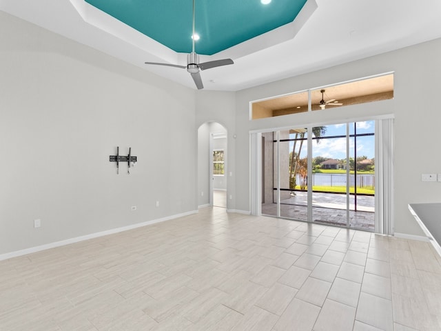 empty room with ceiling fan and a raised ceiling