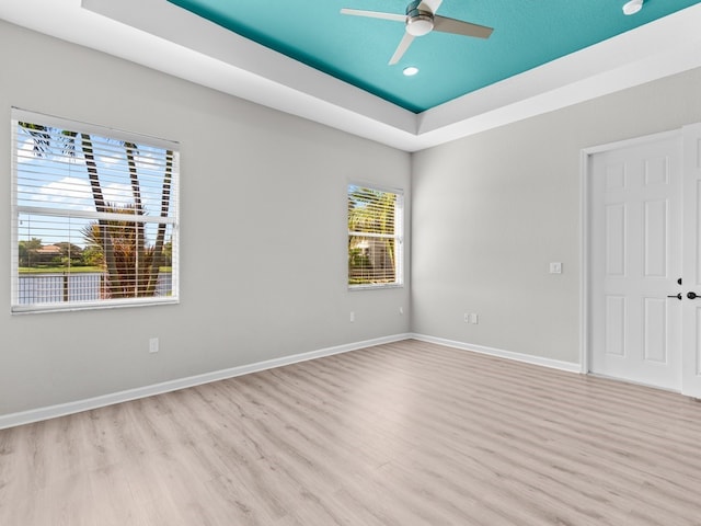 spare room featuring light wood-type flooring, ceiling fan, and a raised ceiling