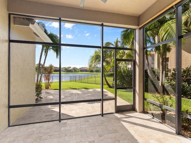 unfurnished sunroom featuring a water view and ceiling fan