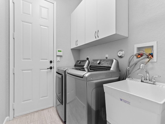 laundry room featuring washing machine and dryer, cabinets, and sink