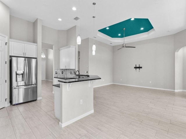 1745 Belmont Cir SW, Vero Beach, FL 32968 - kitchen featuring stainless steel fridge, arched walkways, dark countertops, a breakfast bar area, and backsplash
