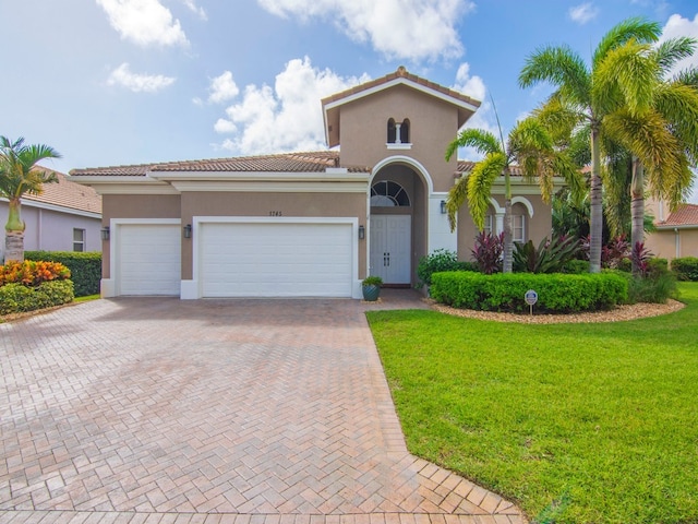 mediterranean / spanish home featuring a garage and a front yard