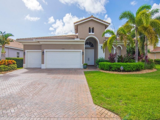 1745 Belmont Cir SW, Vero Beach, FL 32968 - mediterranean / spanish home with decorative driveway, a front yard, stucco siding, an attached garage, and a tile roof