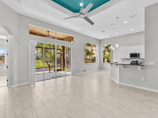 unfurnished living room with ceiling fan and a healthy amount of sunlight