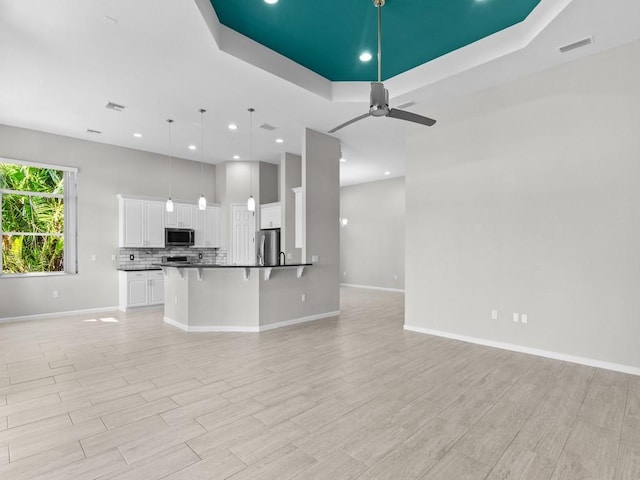1745 Belmont Cir SW, Vero Beach, FL 32968 - unfurnished living room with a raised ceiling, ceiling fan, recessed lighting, and light wood-style floors