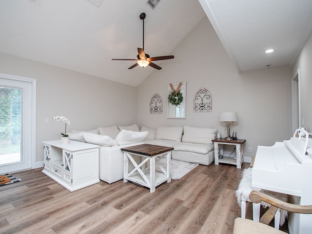 living room with ceiling fan, vaulted ceiling, and light wood-type flooring