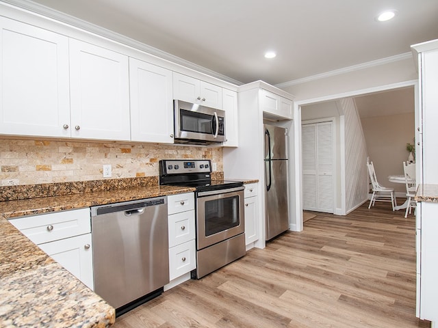 kitchen featuring white cabinets, crown molding, stainless steel appliances, and stone counters