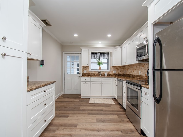 kitchen featuring white cabinets, sink, crown molding, dark stone countertops, and stainless steel appliances