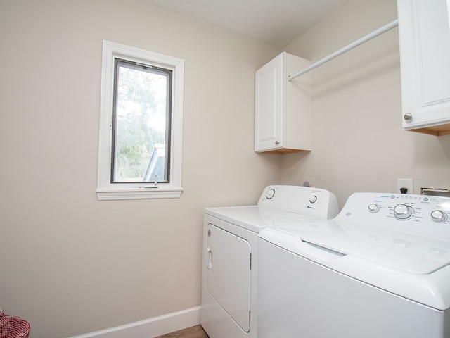 clothes washing area featuring washer and dryer and cabinets