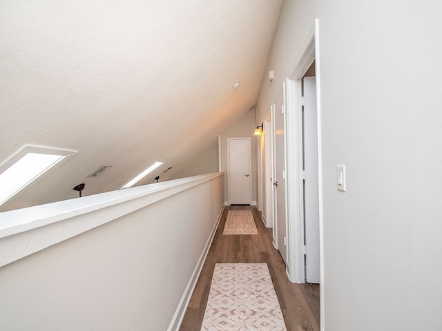 hall with lofted ceiling with skylight and hardwood / wood-style flooring