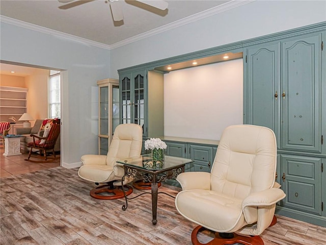 sitting room with ornamental molding, light wood-type flooring, baseboards, and a ceiling fan