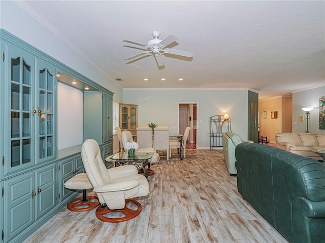 living room featuring light wood-style floors, baseboards, ornamental molding, and a ceiling fan