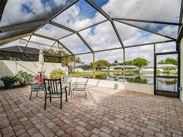 view of patio with glass enclosure and a water view