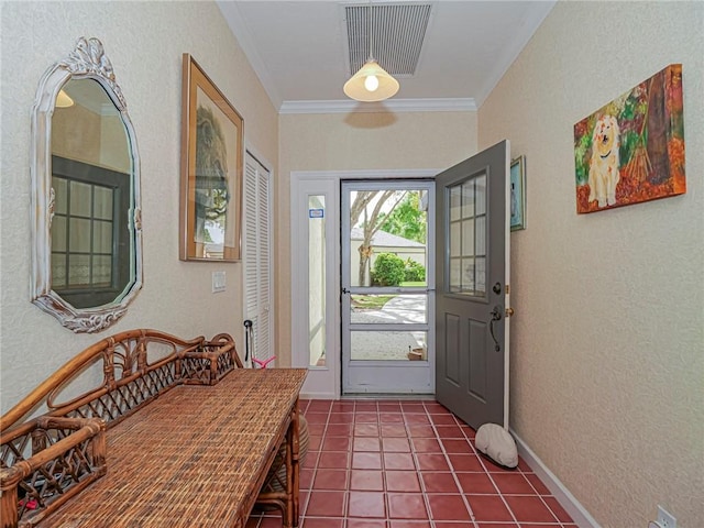 entryway featuring visible vents, a textured wall, ornamental molding, dark tile patterned flooring, and baseboards