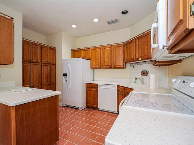 kitchen featuring white appliances, visible vents, brown cabinets, and a sink