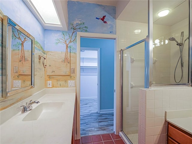 full bath featuring a stall shower, a skylight, vanity, and tile patterned floors