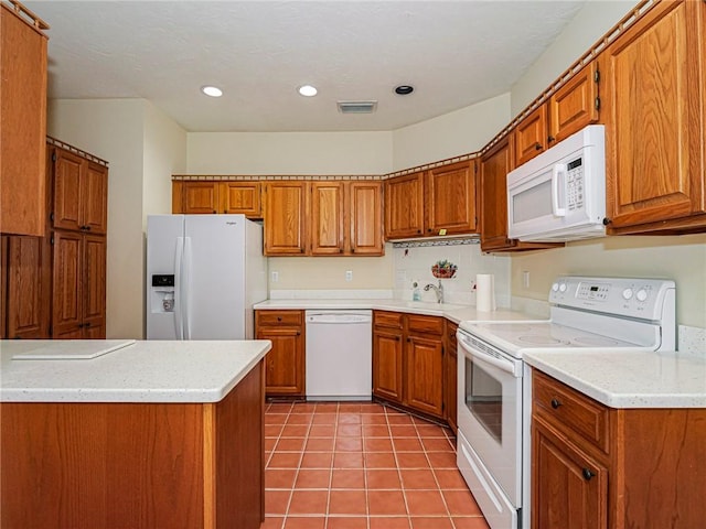 kitchen with white appliances, visible vents, brown cabinets, and light countertops