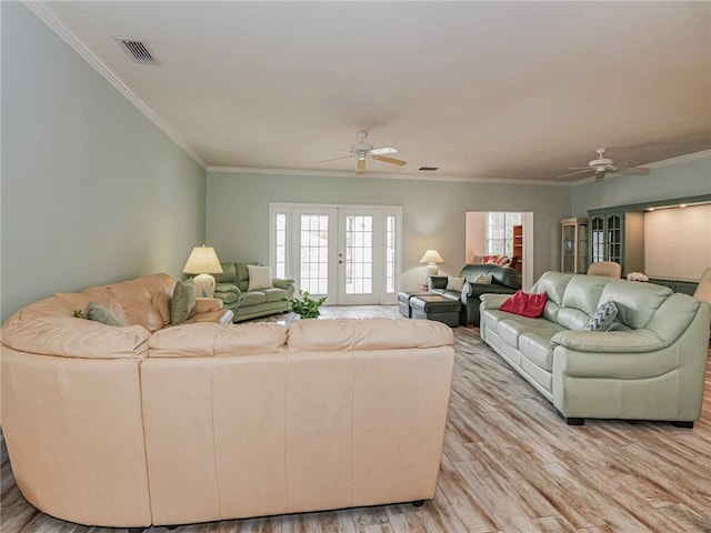 living room with crown molding, visible vents, ceiling fan, and light wood-style flooring