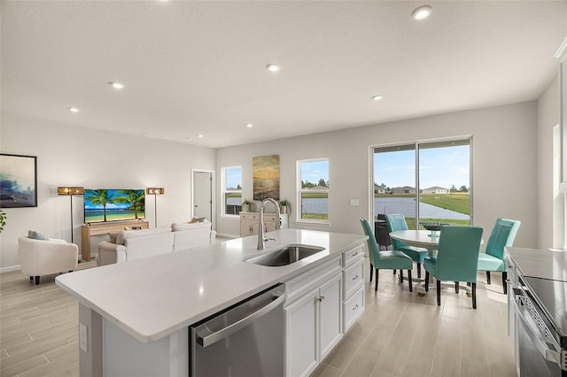 kitchen featuring light countertops, appliances with stainless steel finishes, an island with sink, and a sink