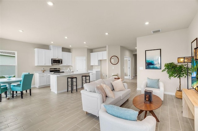 living room with visible vents, baseboards, light wood-style flooring, and recessed lighting