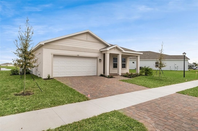 ranch-style house with a garage, a front yard, decorative driveway, and stucco siding