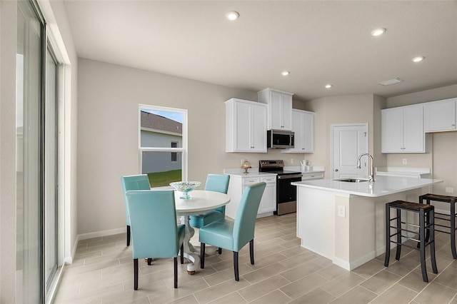 kitchen with appliances with stainless steel finishes, a sink, white cabinetry, and recessed lighting