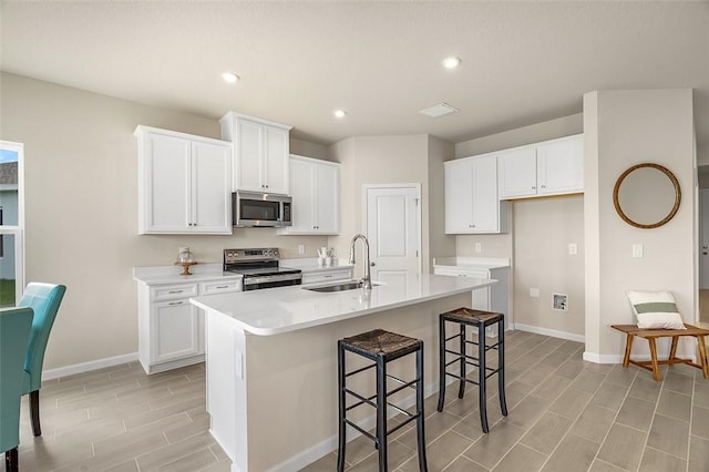 kitchen with baseboards, stainless steel appliances, a sink, and white cabinets