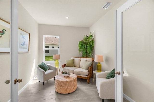 living area featuring french doors, visible vents, and baseboards