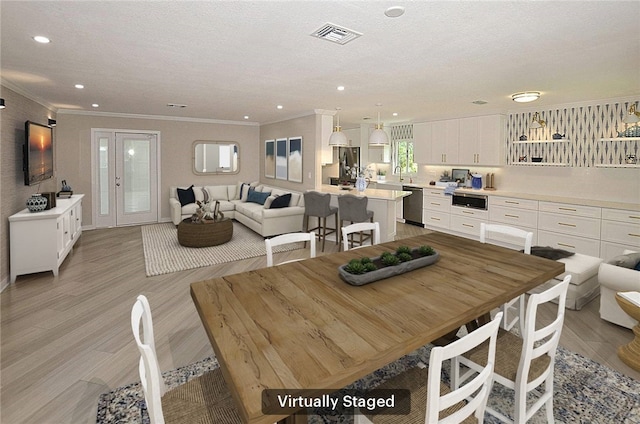 dining area with crown molding, light hardwood / wood-style floors, sink, and a textured ceiling