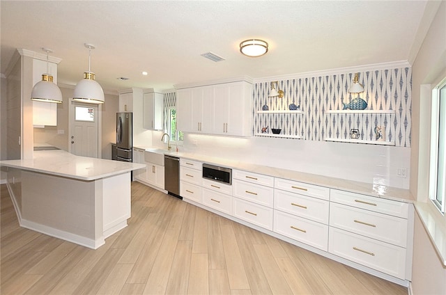 kitchen with pendant lighting, stainless steel appliances, white cabinetry, and plenty of natural light