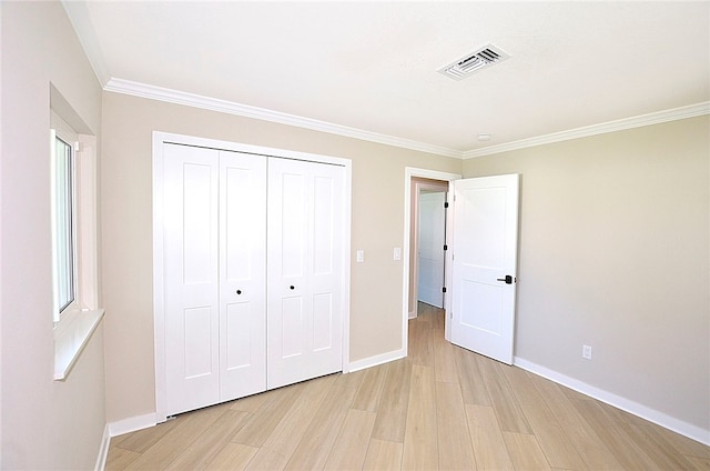 unfurnished bedroom with light wood-type flooring, crown molding, and a closet