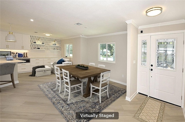 dining space featuring a textured ceiling, light wood-type flooring, and crown molding