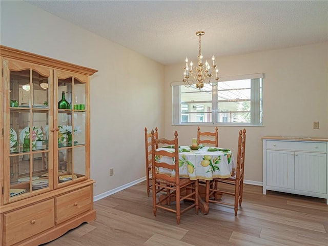 dining room with a chandelier, light wood-type flooring, and baseboards