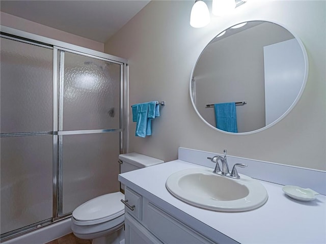 bathroom featuring toilet, a stall shower, and vanity