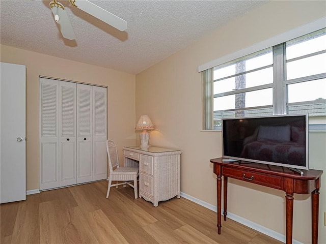 office with light wood-type flooring, a ceiling fan, a textured ceiling, and baseboards