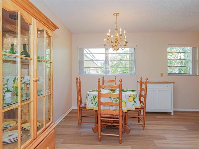 dining room with light wood finished floors, a chandelier, plenty of natural light, and baseboards