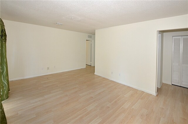 spare room featuring a textured ceiling and light hardwood / wood-style floors