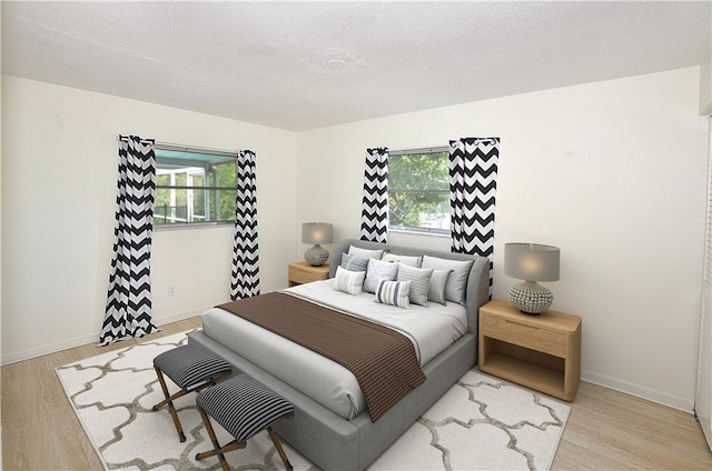 bedroom featuring multiple windows, light hardwood / wood-style flooring, and a textured ceiling