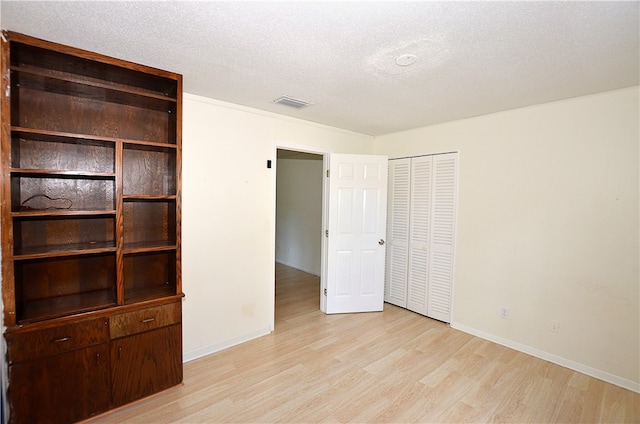 unfurnished bedroom with a closet, a textured ceiling, and light hardwood / wood-style flooring