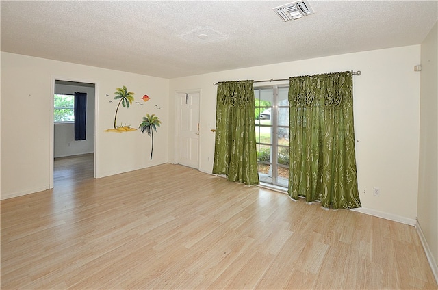 empty room with a textured ceiling and light hardwood / wood-style floors