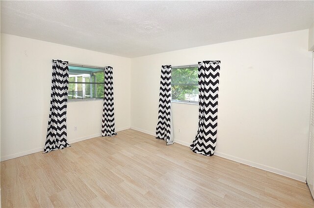 unfurnished room featuring a textured ceiling and light wood-type flooring