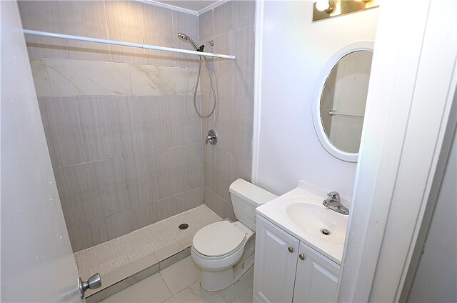 bathroom featuring tile patterned floors, vanity, toilet, and tiled shower